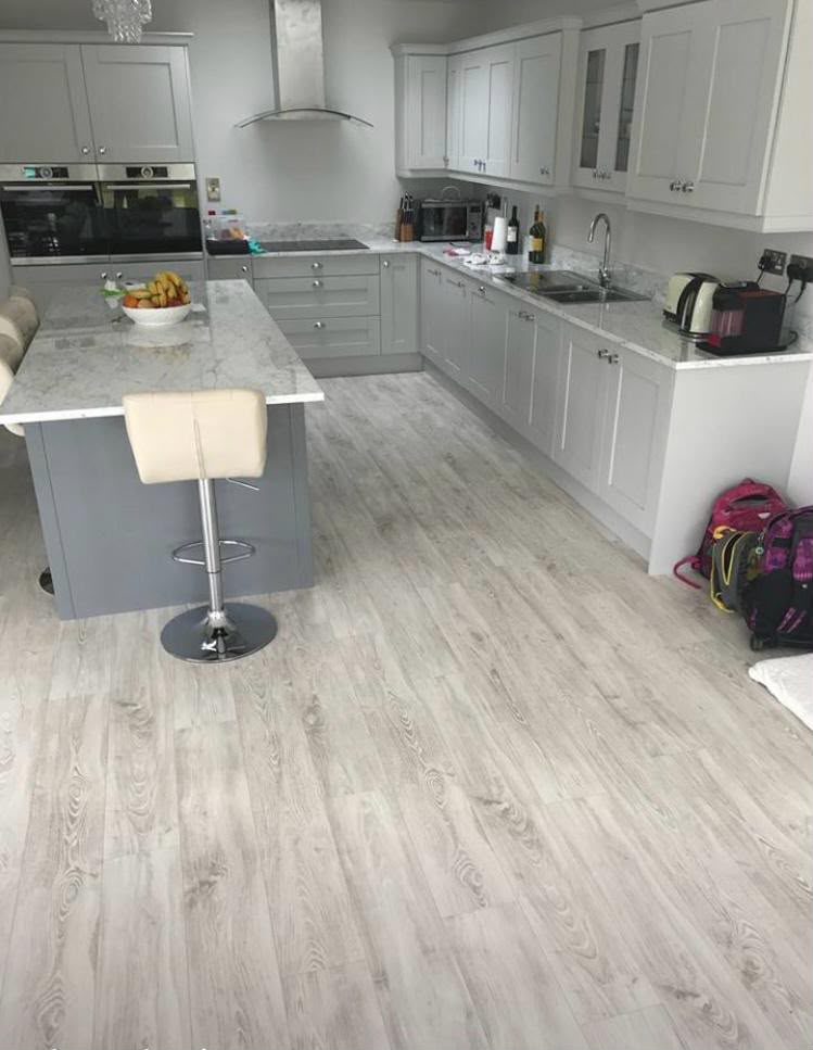 Renovated open-plan kitchen with grey shaker units and new plank flooring