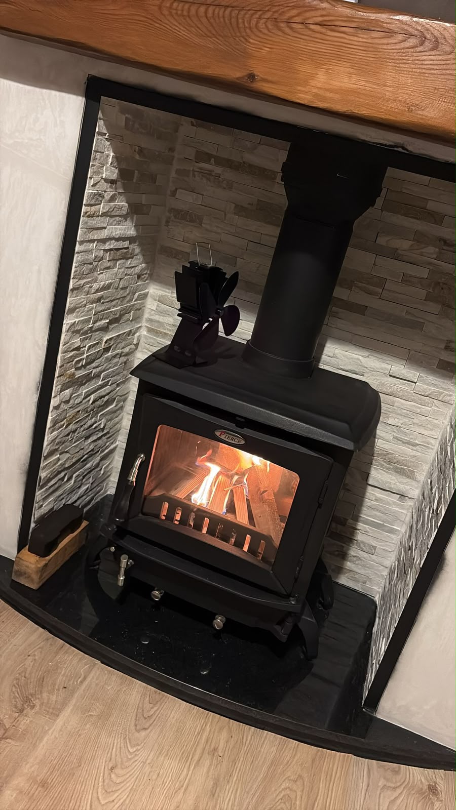 New solid-fuel stove installation with stone-effect surround and timber mantel